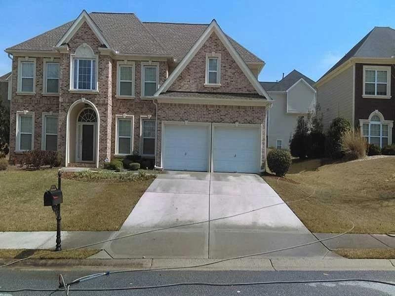 Freshly cleaned concrete driveway in front of a two-story brick home