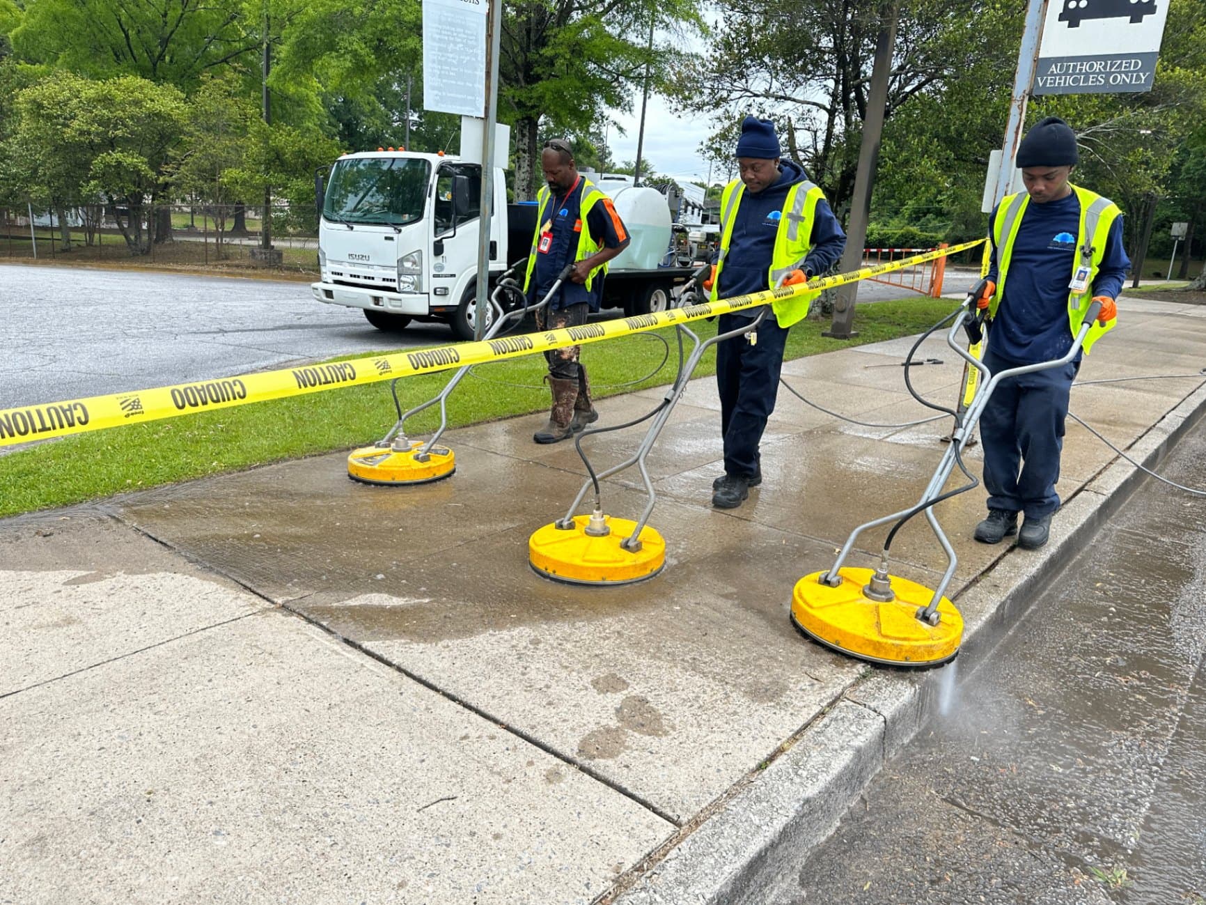 Three Buck A1 technicians cleaning a public sidewalk with surface cleaners