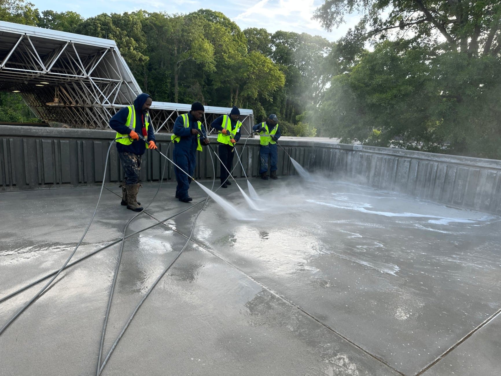Four Buck A1 technicians pressure washing a large concrete deck